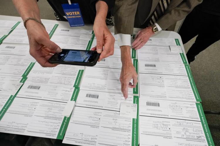 A canvas observer photographs Lehigh County provisional ballots as vote counting in the general election continues, Nov. 6, 2020, in Allentown, Pa. (AP Photo/Mary Altaffer)
