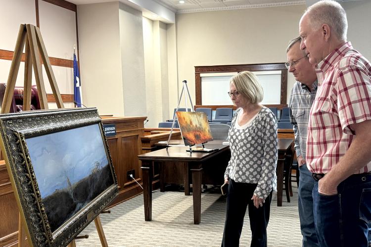 Commissioners Dawn Webb, Dale Schafer and Tim Alexander study "Perseverance," painting commemorating Smokehouse Creek Fire, which will hang in Hemphill County Courthouse