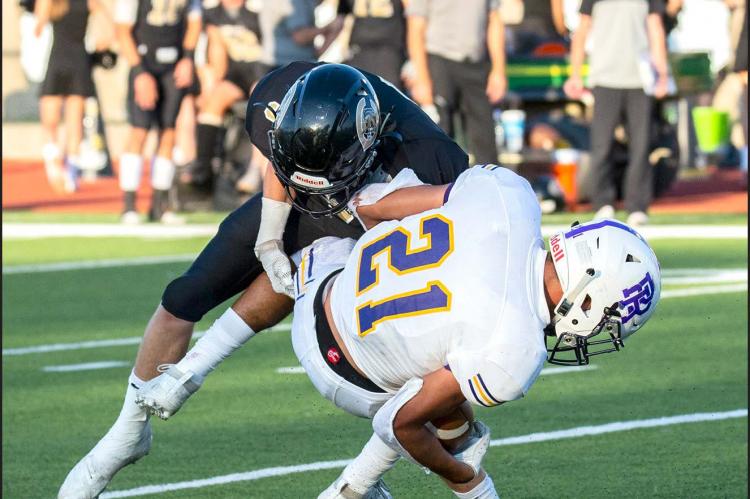 CAUGHT IN A TWISTER: River Road’s running back (21) is upended by Twister Kelton (3) last Friday night at Wildcat Stadium. Canadian won 42-14 to go 2-0 on the season.