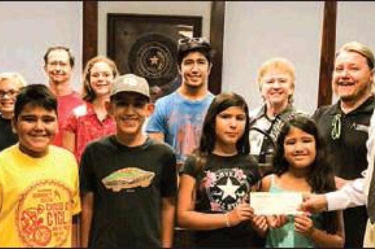 CANADIAN COMMUNITY CENTER: Canadian Area Legacy Fund Advisory Committee member George Briant (at right in photo) presents a $5,000 check to the CCC; (back, l-r) CALF rep. Terrill Bartlett; Tucker Landry; CALF rep. Larry Smith; CCC members, Ainsley Cook and Adrian Avila, CALF rep Sherye Talley; CCC Assistant Director Ike Julian; (front) CCC members, C.J. Jimenez, Aiden Meraz, Victor Meraz, Jasmine Avila, and Sofia Avila.