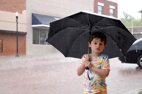Atticus Weeks wielded a mighty big umbrella Tuesday evening as he stood outside the Palace Theatre and watched the downpour. 