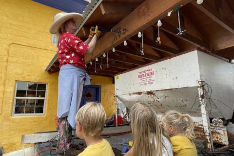 Beth Ramp Sturgeon burns the Ramp Ranch brand into the main beam of the Last Cowboy’s porte cochere, as Joshua, Ella and Elsie Tubb, children of Wyatt and Anna Tubb, and grandchildren of David and Sue Tubb.