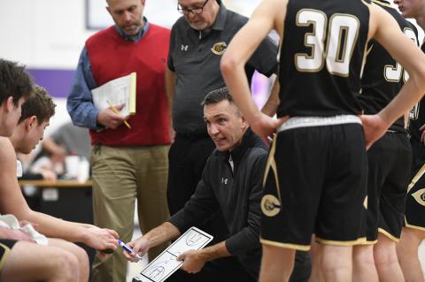In a recent basketball game, Wildcat Coaches Isom, Merket, and Wall huddle with the team during a timeout to work on strategy.