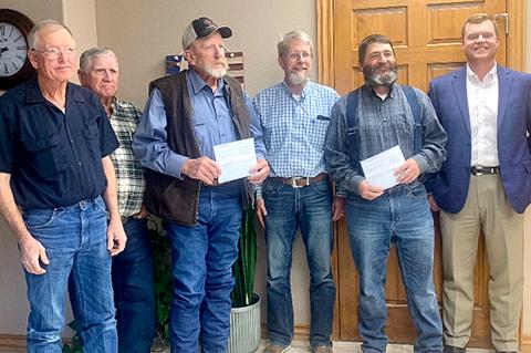 Farm Bureau representatives Carey Keeton, Kenny Wicker, Gene Franks, and (at far right) John Haley present checks to fire chiefs David Pearson, Briscoe VFD; Kyle Barnett, Gem City VFD; and Scott Brewster, Canadian VFD, who was not present. 