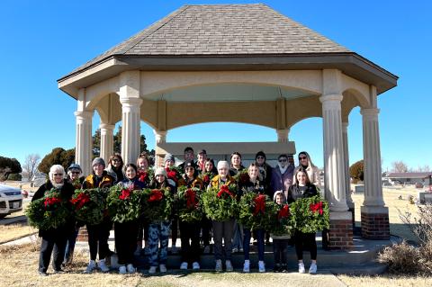 Many of the volunteers gathered at the cemetery gazebo for a photo before beginning the task of laying wreaths on veterans' graves