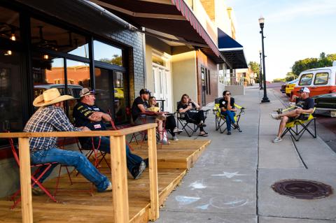 Car aficionados relax on the deck at Brown Bag Roasters as a fleet of classics, street rods, project cars, roadsters and other chrome-clad treasures arrive