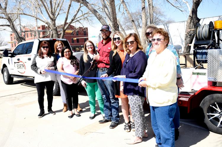Ashton and Travis wield a pair of scissors to cut the official ribbon, flanked by Chamber board members and employees: Michelle Schaef, Lawana Pulliam, Araceli McPherson, Sarah Rader, Betsy Alexander, Jackie McPherson, and Sherye Talley
