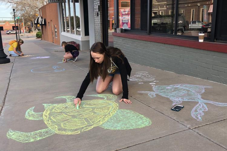 Clara Pulliam and friends create chalk art in front of Brown Bag Roasters Thursday