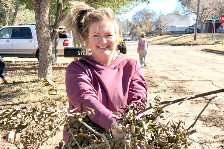 Church of Christ secretary Darcey Whitson pauses and smiles for a photo while cleaning up limbs.