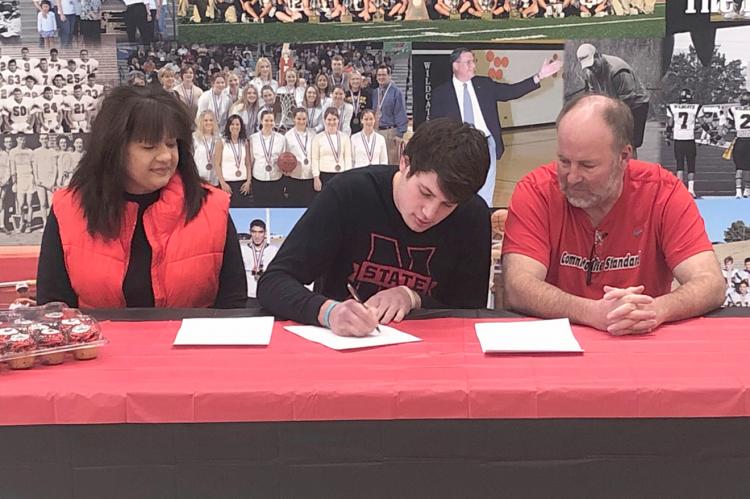 Coach Jay McCook and wife Lynn look on with pride as their son, Grant, signs a letter of intent with Northwestern Oklahoma State University. 