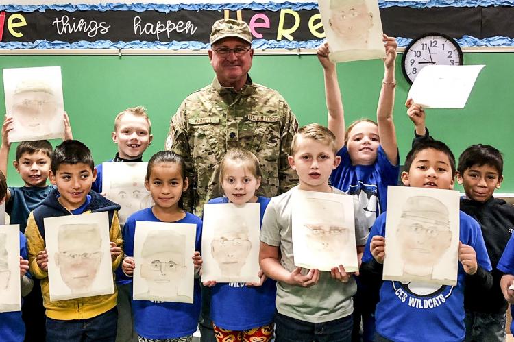 Veteran David Parnell poses with his portraits from Esmeralda Shields’ second graders.