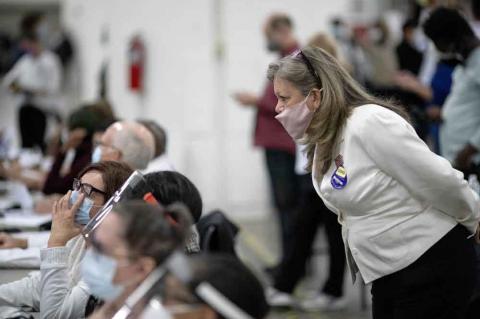 A Republican election challenger at right watches over election inspectors as they examine a ballot as votes are counted into the early morning hours, Nov. 4, 2020, at the central counting board in Detroit. (AP Photo/David Goldman)