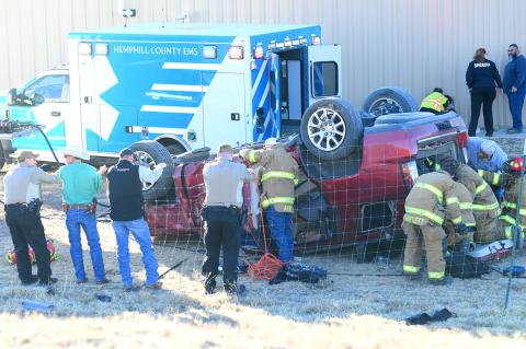 Hemphill County sheriff's officers, EMS paramedics, and Canadian volunteer firefighters work carefully to extricate the last victim from the overturned vehicle Friday afternoon, as other firefighters extinguish a small fire along Exhibition Road. 