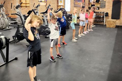 The CCC kids limber up before their coach, Sawyer Landry, runs them through the paces in the Fit Kids exercise program Monday