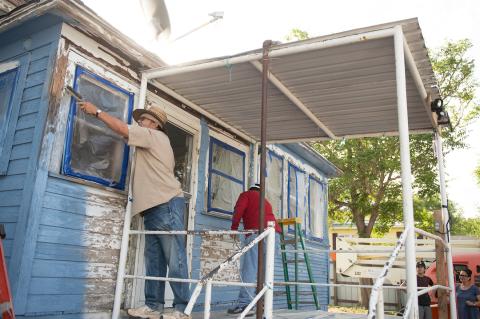 Doug Benge and Mario Flores apply a fresh coat of paint to this home