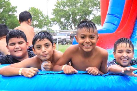Hondo Cervantes, Alan Soto, and Axel Alavera get relief from the heat on the blow-up water slide