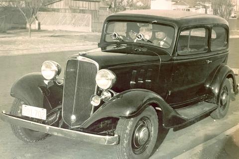 Sheriff Jones and Deputy Sheriff Oney sitting in a 1933 Chevrolet Master Coupe with guns sticking out of the mounts of the bulletproof windshield 