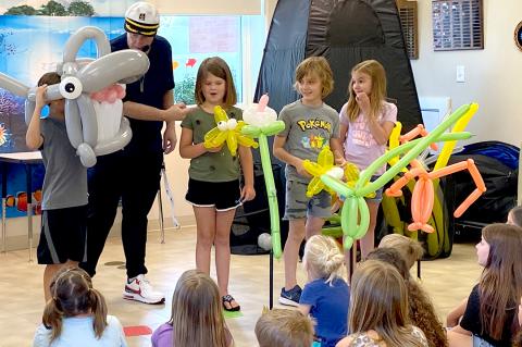 Mateo Lopez becomes the balloon shark (at left), and Maddilyn Allison, Baxter Landry, and Kota Shrader react to his giant teeth, just before he loses them
