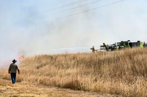 Canadian firefighters attempt to stop the spread of a fire that started across the highway at Vaca Corrales Feedyard, despite gusty 30-40 mph winds and an abundance of dry fuel for the flames to feed on. 